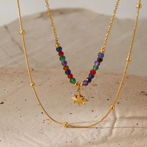 Nahaufnahme der zweilagigen Goldkette mit bunten Perlen und einem Stern-Anhänger