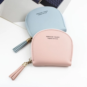 Pastel pink and blue shell-shaped zip wallets with tassels on white background