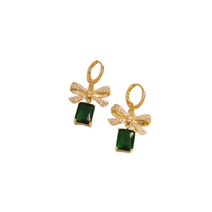 Elegant gold bow earrings with green zircon stones and sparkling crystals on white background