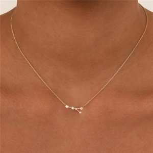 Close-up of a gold constellation necklace with star pendant and zircon on female collarbone
