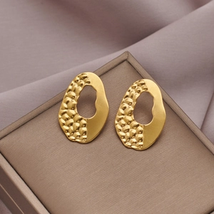Detail of gold bow earrings featuring hammered texture and polished mirror finish