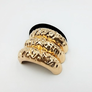 Detail of vintage gold alloy hair tie with textured metal relief and elastic band