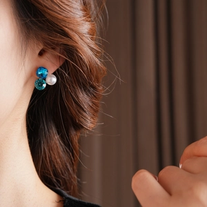 Detail of luxury triangle pearl earrings with sparkling blue crystals on female model