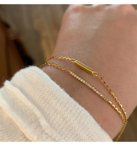 Close-up of minimalist layered gold bracelets with a sleek bar and micro-pave crystals