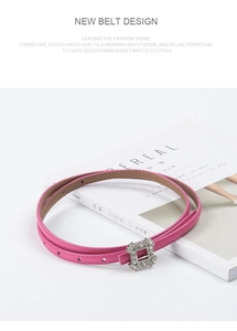 Detailed view of pink leather belt with square silver rhinestone buckle on white magazine