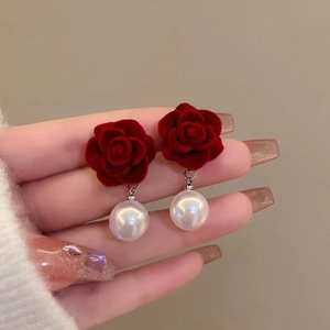 Détail de boucles d'oreilles rose en velours rouge avec perles blanches et clous en argent