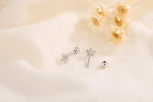 Macro shot of silver flower earrings with screw back design on beige linen fabric