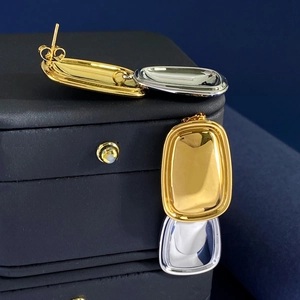 Detailed close-up of rectangular titanium steel earrings in gold and silver finish