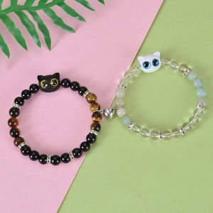 Close-up of magnetic heart clasp connecting black and green beaded cat bracelets