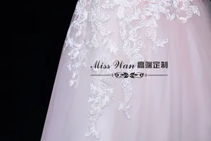 Détail de l'applique florale en dentelle blanche sur le tulle rose clair de la robe