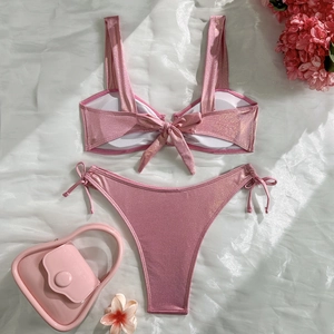 Detailed flat lay of pink metallic glitter bikini with side-tie bottoms on white silk