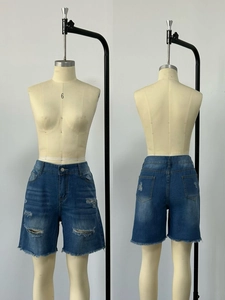 Dettaglio di pantaloncini in denim blu con strappi usurati e orli a frange per donne
