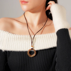 Detailed view of a vintage resin round pendant necklace on a model with neutral tones