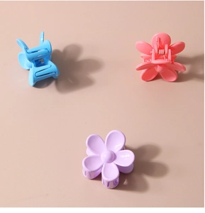 Detailed macro view of matte flower hair claws in pastel blue, pink, and purple colors