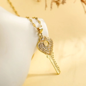 Gold-plated key pendant necklace with a zircon-encrusted heart on a white display base