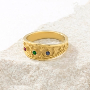 Macro detail of a vintage gold ring with colorful gemstones and textured metalwork