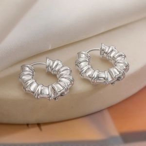 Boucles d'oreilles créoles argentées texturées sur un élégant socle en pierre blanche
