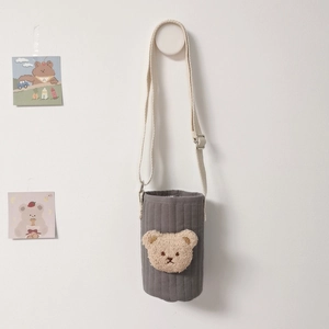 Quilted gray cup holder with a beige plush bear detail and adjustable shoulder strap