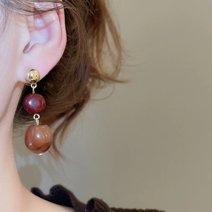 Close-up of elegant resin bead drop earrings with gold and marble finish on ear