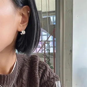 Close-up of minimalist S925 silver C-shape earrings with pearls and a tiny star stud