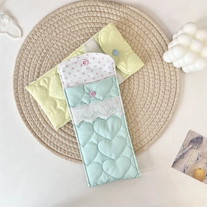 Detail of heart quilted glasses pouches with lace trim and snap closure on straw mat