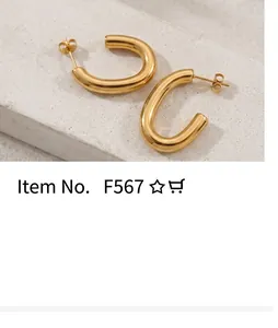 Polished gold U-shaped hoop earrings with butterfly backs on a textured stone surface