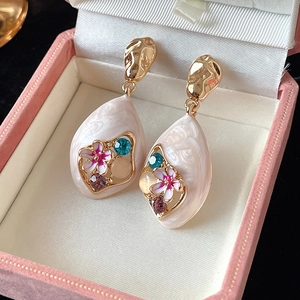 Macro view of teardrop earrings with floral metalwork and colorful crystals in a velvet box