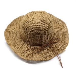 Detail of hand-woven straw hat featuring a wide wavy brim and a brown rope bow accent