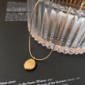 Close-up of gold snake chain necklace with engraved you are adorable pebble pendant