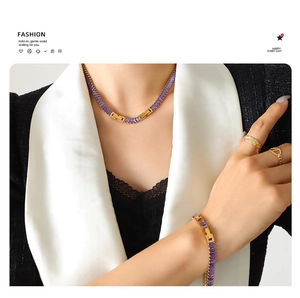 Detail of model wearing purple zircon pendant necklace, bracelet and gold rings set