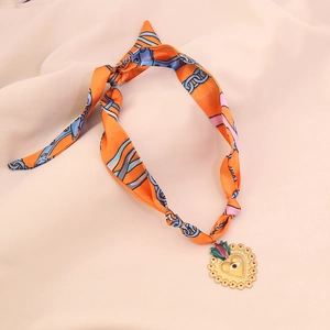 Detailed view of colorful silk scarf necklace featuring a gold heart and eye pendant