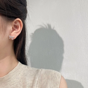 Close-up of a model wearing sparkling silver bow stud earrings with pavé set crystals