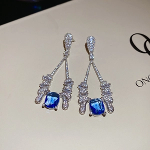 Detailed view of long hollow drop earrings with blue cubic zirconia in silver setting