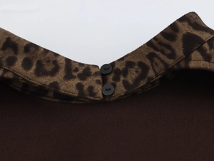 Detail eines Leopardenmusters am Kragen auf braunem Oberteil mit zwei schwarzen Knöpfen