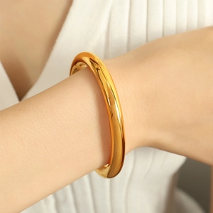 Polished chunky gold titanium steel C-shaped cuff bracelet shown on female model wrist