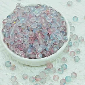 Macro detail of 6mm frosted pastel glass beads with gold foil inside a white ceramic bowl