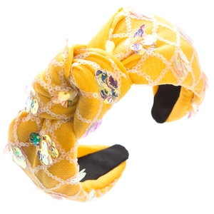 Detailed view of yellow knotted headband with colorful sequins and white mesh overlay