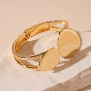 Detail of a gold irregular geometric open bangle set on a white textured stone