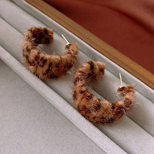 Detail of C-shaped leopard print earrings with soft flocking texture in brown tones