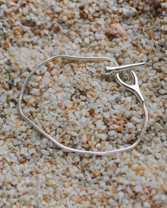 Close-up of silver snake chain necklace with OT toggle clasp on natural stone background