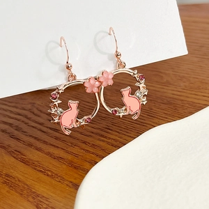 Detail of pink enamel cat earrings with sakura blossom and rose gold finish
