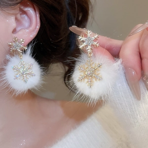 Macro shot of snowflake earrings with sparkling rhinestones and white pom pom pendants
