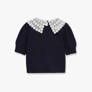 Macro shot of white crocheted lace Peter Pan collar on navy blue knit sweater