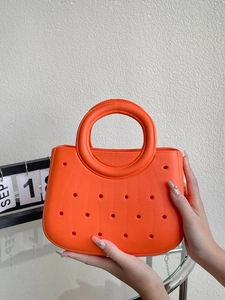 Détail du sac de plage orange vif en EVA avec design perforé circulaire et poignée souple