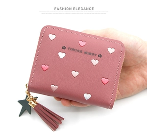 Detail of pink leather wallet with heart embroidery, tassel and star pendant