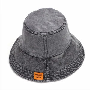 Dettaglio ravvicinato di cappello bucket in denim grigio scuro con patch arancione ricamata