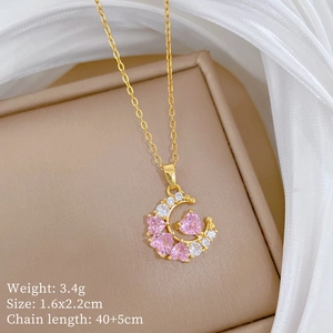 Detail of gold crescent moon necklace with pink heart crystals and white silk background
