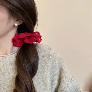 Detail of red hollow lace scrunchie with intricate textures on long brown hair