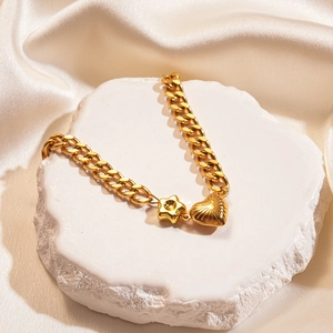 Macro detail of gold textured heart and star charms on a chunky stainless steel link chain
