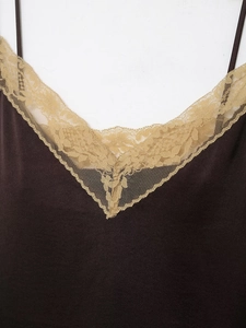Detailed close-up of dark brown satin camisole with golden yellow lace V-neckline
